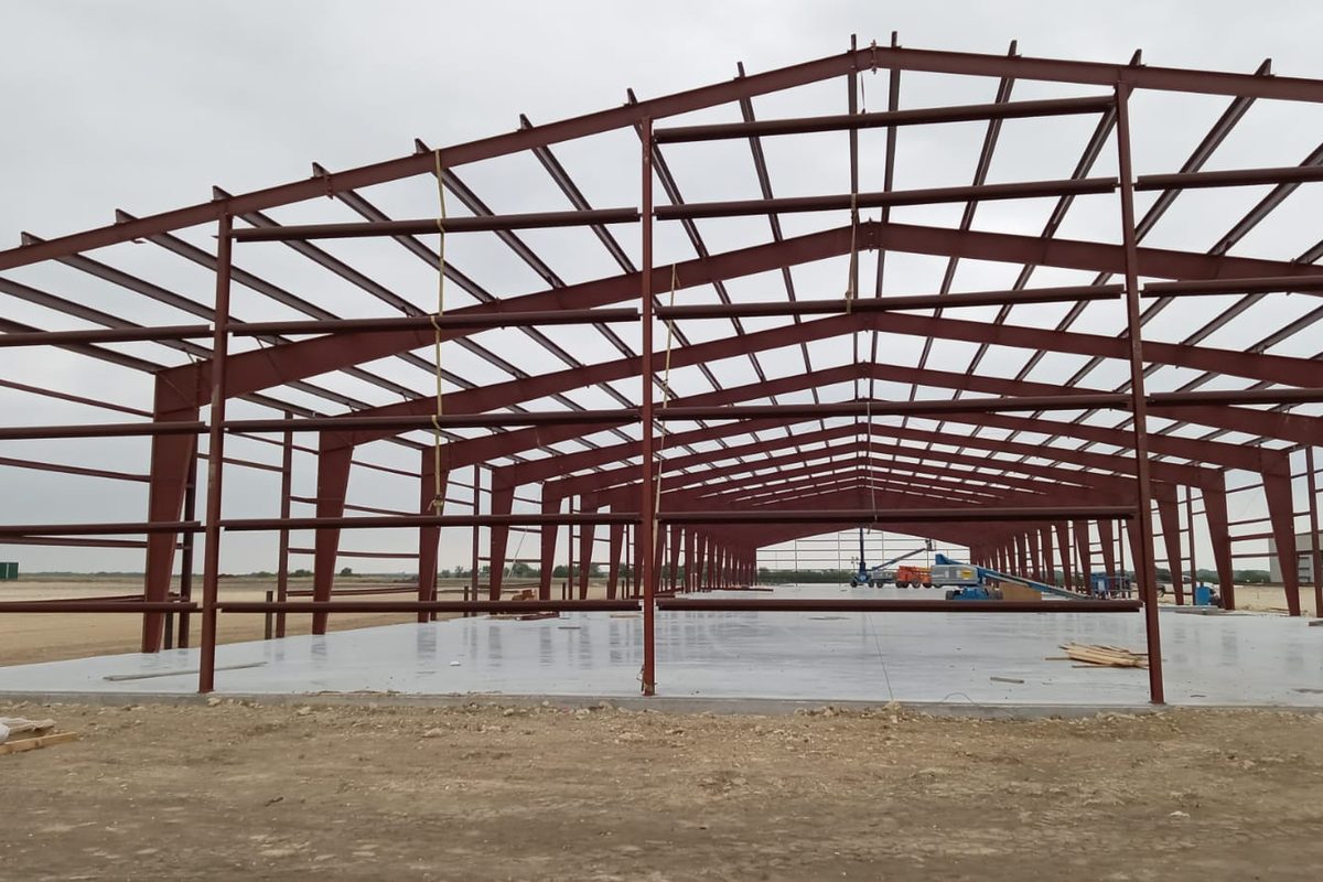 Red-iron structural frame of a commercial metal building on a poured slab